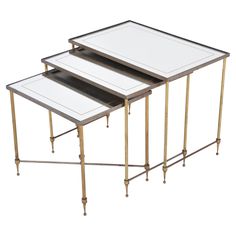 three metal and glass nesting tables with gold trimmings on each side, one is white