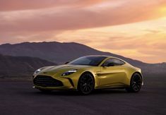 a yellow sports car is parked in front of some mountains at sunset or dawn with the sun setting behind it