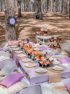 a picnic table set up in the woods with plates and napkins laid out on it