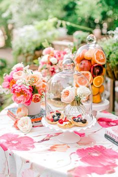 a table with flowers and fruit under a cloche dome