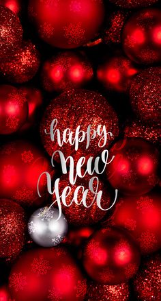 red christmas balls with the words happy new year written in white lettering on them, surrounded by shiny ornaments