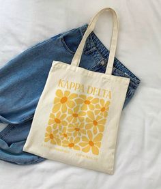 a tote bag sitting on top of a bed next to a pair of jeans