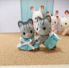 two small stuffed animals sitting next to each other on top of a counter with mice in the background