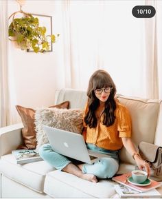 a woman sitting on a couch using a laptop computer