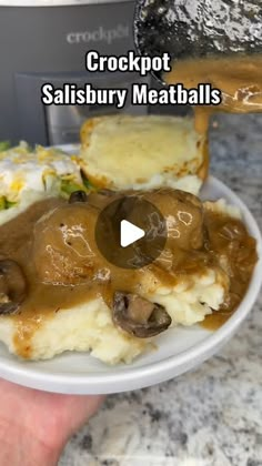 a person is holding a plate with mashed potatoes and gravy on it