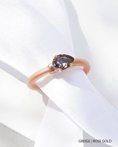 a close up of a ring on top of a white cloth with a diamond in the middle