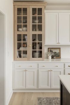 a kitchen with white cabinets and wood floors