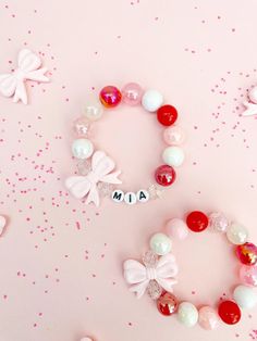 two bracelets with name and bows on them sitting next to confetti sprinkles