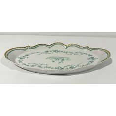 a white and green platter with gold trimmings on the edge, sitting on a table