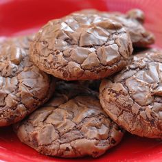 chocolate cookies are piled on top of each other in a red bowl, ready to be eaten