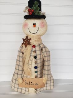 a stuffed snowman wearing a hat and coat with the word believe written on it