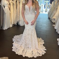 a woman is standing in front of some wedding gowns on display at a bridal shop