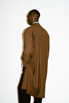 A pared-down sartorial classic with an irreverent twist. This statement structural coat is tailored to perfection with sharp, broad shoulders and clean lines. Constructed in a supremely soft & fluid 100% lightweight wool that drapes below the knee, this layer offers a dose of sophistication to transitional dressing. Elegant Oversized Brown Wool Coat, Spring Outerwear With Structured Boning, Modern Outerwear With Structured Boning, Oversized Long Wool Coat For Work, Modern Structured Outerwear With Boning, Tailored Solid Outerwear With Pressed Crease, Modern Long Sleeve Outerwear With Structured Boning, Elegant Oversized Outerwear For Business, Modern Structured Boning Outerwear For Spring