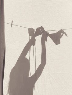 the shadow of a person hanging clothes on a line