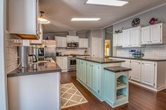 a large kitchen with white cabinets and wood flooring, along with an island in the middle