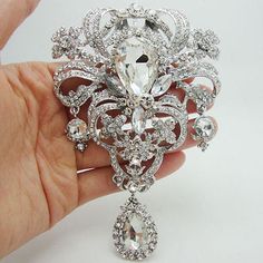 a woman's hand holding a crystal brooch with diamonds on the bottom and sides