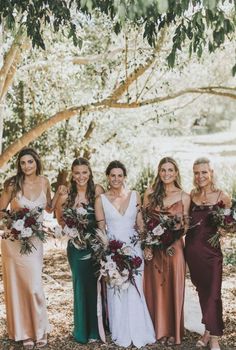 a group of women standing next to each other wearing dresses and holding bouquets in their hands