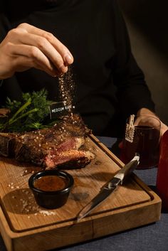 a person is cutting up some meat on a wooden board with sauces and seasonings