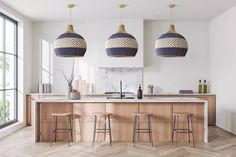 three pendant lights hanging from the ceiling above a kitchen island with stools in front of it