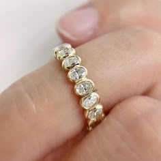 a woman's hand holding a gold ring with five small round diamonds on it