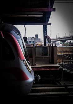 a red and white train traveling down tracks next to a loading platform at a station