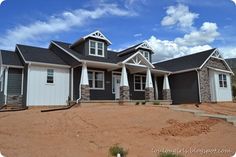 a large house with two garages and three windows on the front, surrounded by dirt