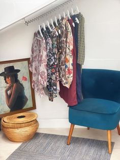 a blue chair sitting in front of a wall with clothes hanging on it's hangers