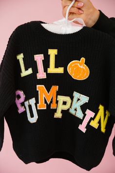 someone is holding up a sweater with the words lil pumpkin on it and an orange