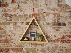 a triangle shaped shelf hanging on a brick wall