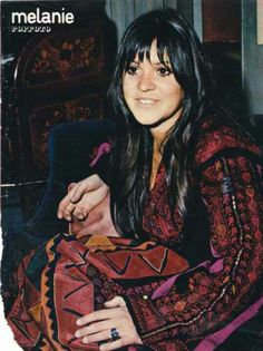 a woman sitting on top of a couch next to a table with a red blanket