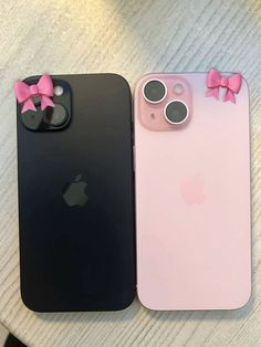 two iphones with bows on them are sitting next to each other, one is pink and the other is black