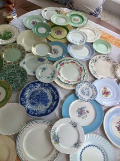 a table topped with lots of plates on top of a white cloth covered floor next to a window