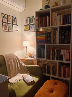 a living room filled with lots of books on top of a book shelf next to a green chair