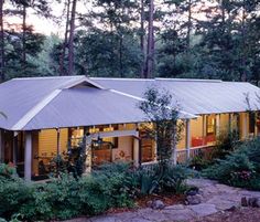 a house in the woods with trees and bushes around it at dusk or sunrise time