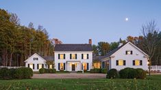 a large white house sitting in the middle of a lush green field