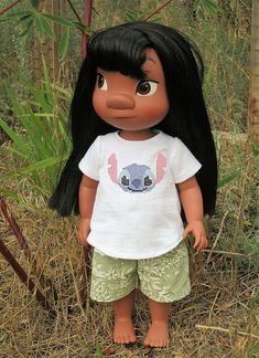 a doll is standing in the grass with long black hair and wearing a white shirt