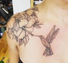 a woman's chest with a hummingbird and flowers tattoo on her left side