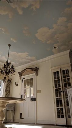 a dining room with a chandelier and clouds painted on the ceiling