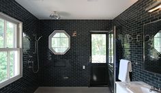 a black and white tiled bathroom with double sinks, mirrors, and shower head mounted to the wall