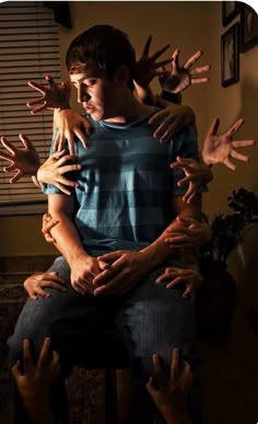 a group of people sitting on top of each other with their hands in the air