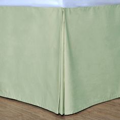 a bed with a light green bedskirt and white sheets