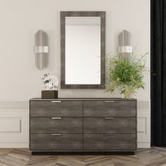 a large mirror sitting on top of a dresser next to a vase with a plant