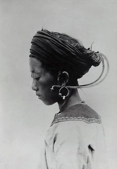 an old photo of a woman with large hoop earrings on her head and hair pulled back