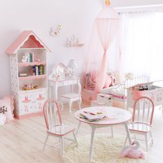 a child's room decorated in pink and white with toys on the table, chairs, bookshelf and doll house