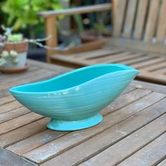 a blue bowl sitting on top of a wooden table next to potted planters