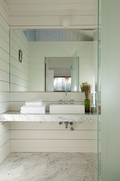 a bathroom with marble counter tops and white walls, along with a large mirror above the sink