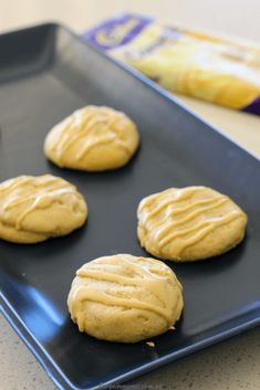 four cookies on a cookie sheet with peanut butter frosting in the middle, ready to go into the oven