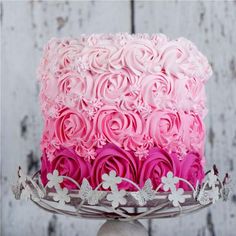 a cake with pink frosting and white flowers is on top of a silver platter