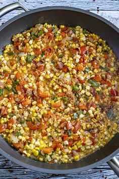 a pan filled with corn and vegetables on top of a wooden table