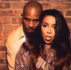 a man and woman standing next to each other in front of a brick wall